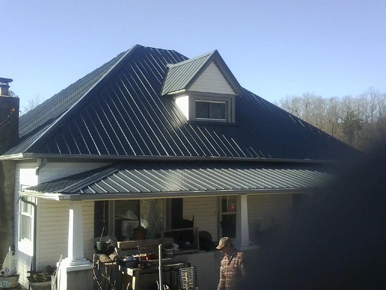 Dark blue standing seam metal roof with a dormer above a front porch in East Wareham
