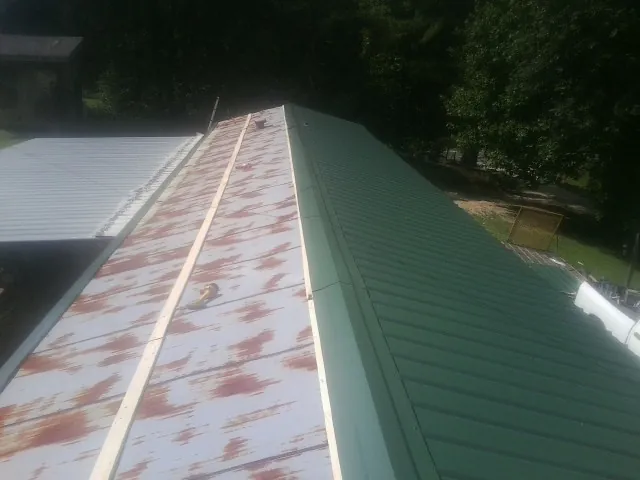 Old rusted panels beside newly installed green metal roofing — Wind Damage Roof Repair by Roofing Brothers in East Wareham