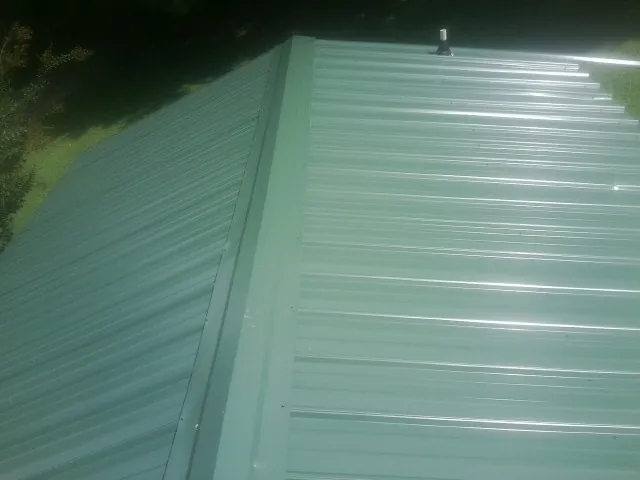 New green metal panels meeting at the ridge of a roof — Flat Roof Repair work by our crew in East Wareham