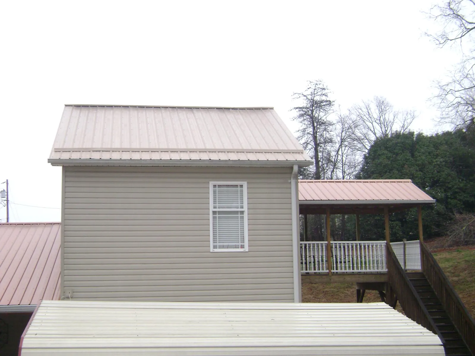 Tan metal roofs on a two story addition and attached porch, from a Roof Replacement job in East Wareham